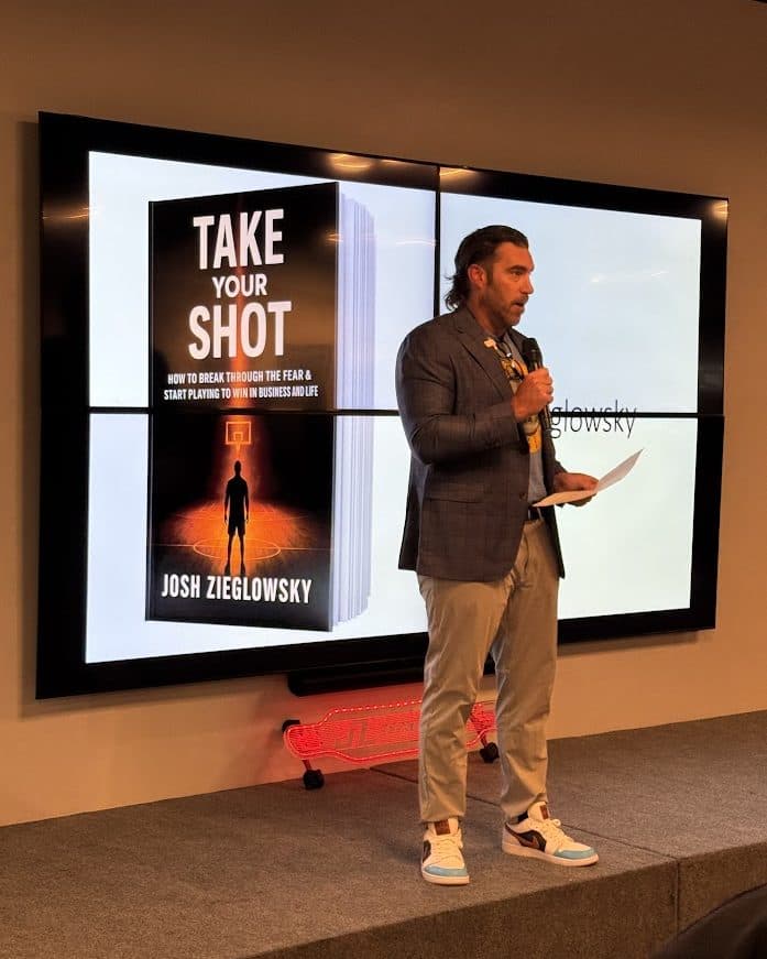 Josh Zieglowsky on stage, Take Your Shot on the screen behind him