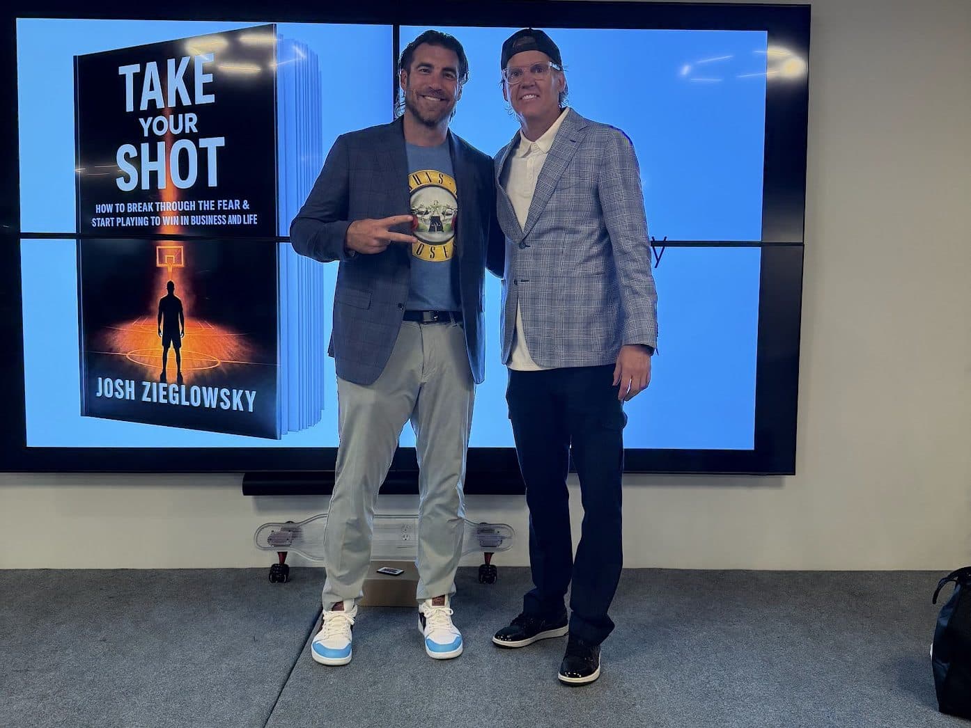 Josh Zieglowsky, left, with Sean Finnegan, in front of a screen showing the cover of Take Your Shot